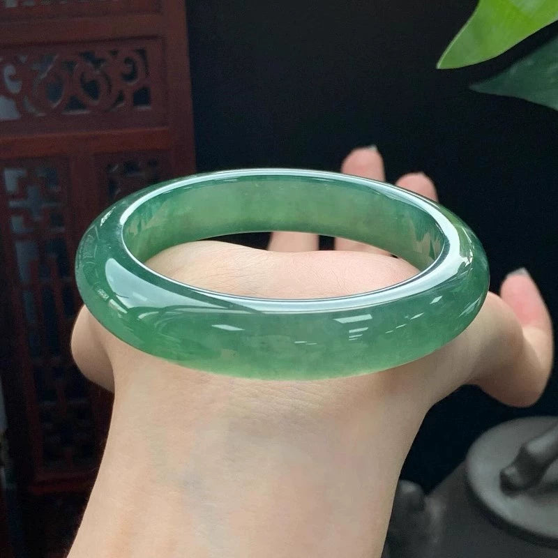 Natural emerald green jadeite bangle bracelet held in hand, showing elegant round shape | DIY Jade
