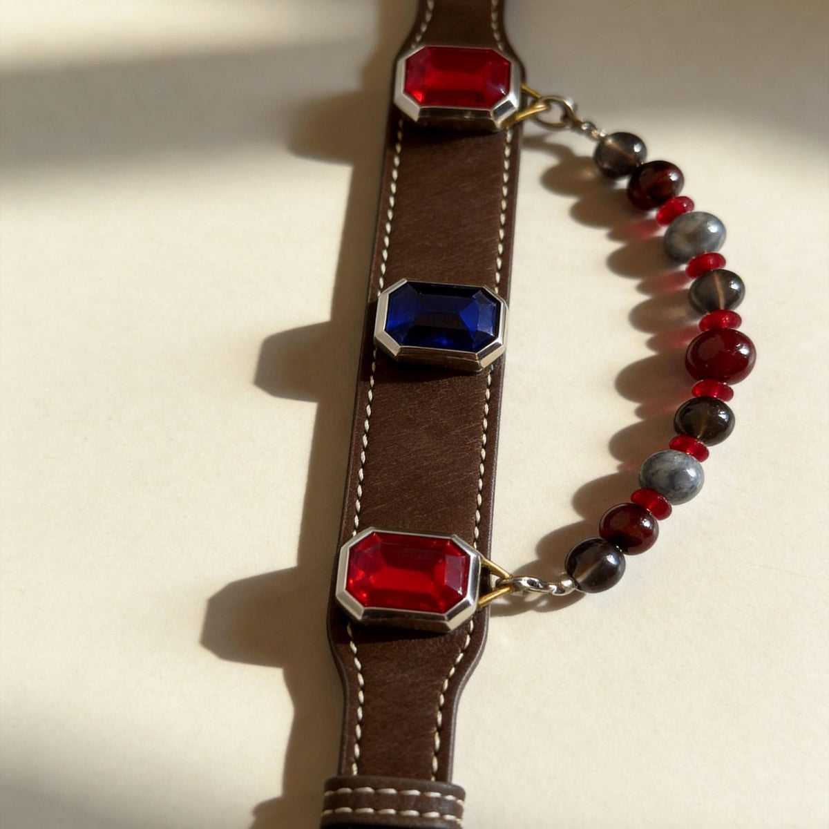 Flat lay shot of brown leather pet collar with alternating red blue gems and polished jade beads | DIY Jade