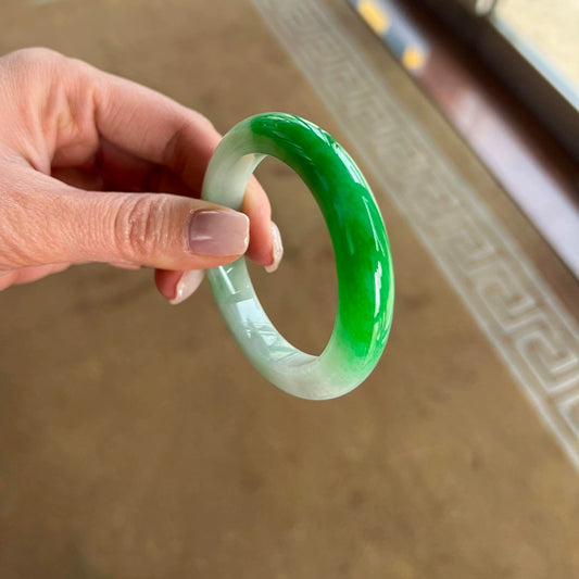 Half green and white gradient jadeite bangle held in hand, showing vivid color transition | DIY Jade