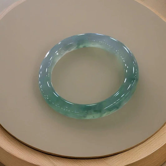 Natural icy light green floating flower jadeite bangle on wooden tray, showing glossy texture | DIY Jade
