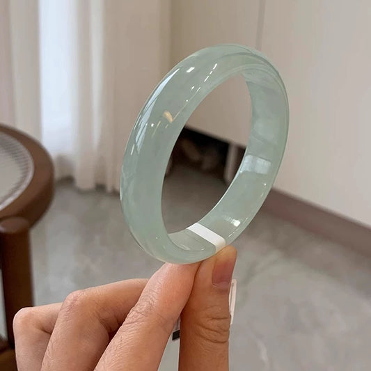 Natural icy light green jadeite bangle, held by finger to show glossy finish and full shape | DIY Jade
