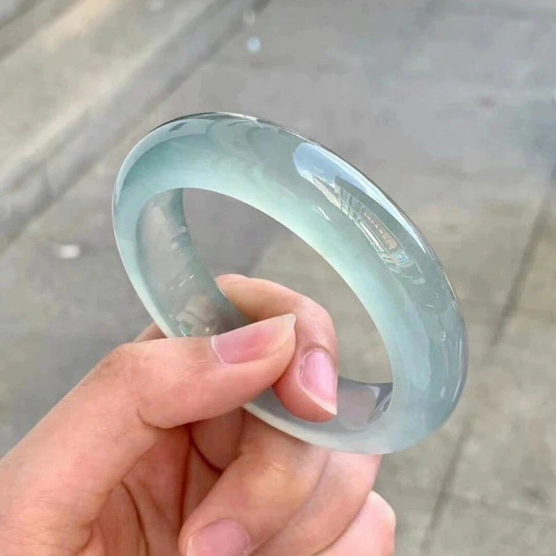 Icy pale green jade bangle held in hand under natural light, showing crystal clear texture | DIY Jade
