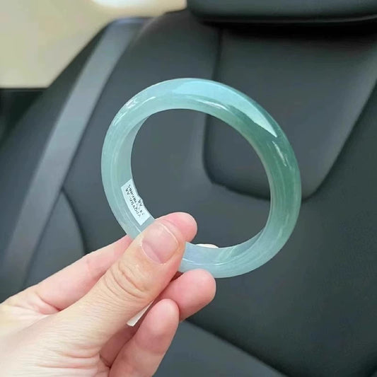 Natural icy pale green jadeite bangle bracelet, held in hand inside car, showing clear texture | DIY Jade