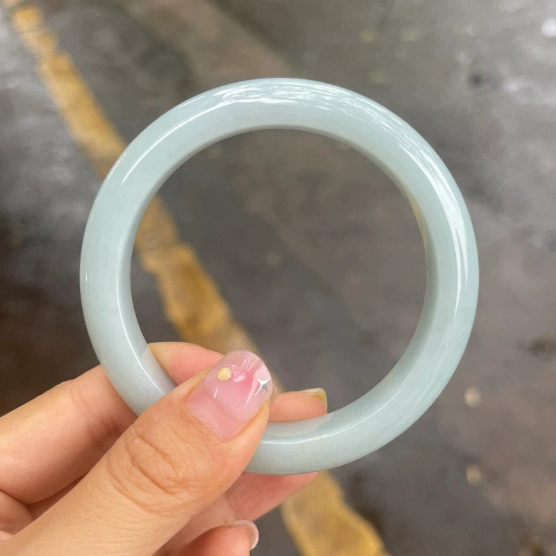 Natural icy pale white jadeite bangle, close-up view showing smooth round shape and glossy finish | DIY Jade
