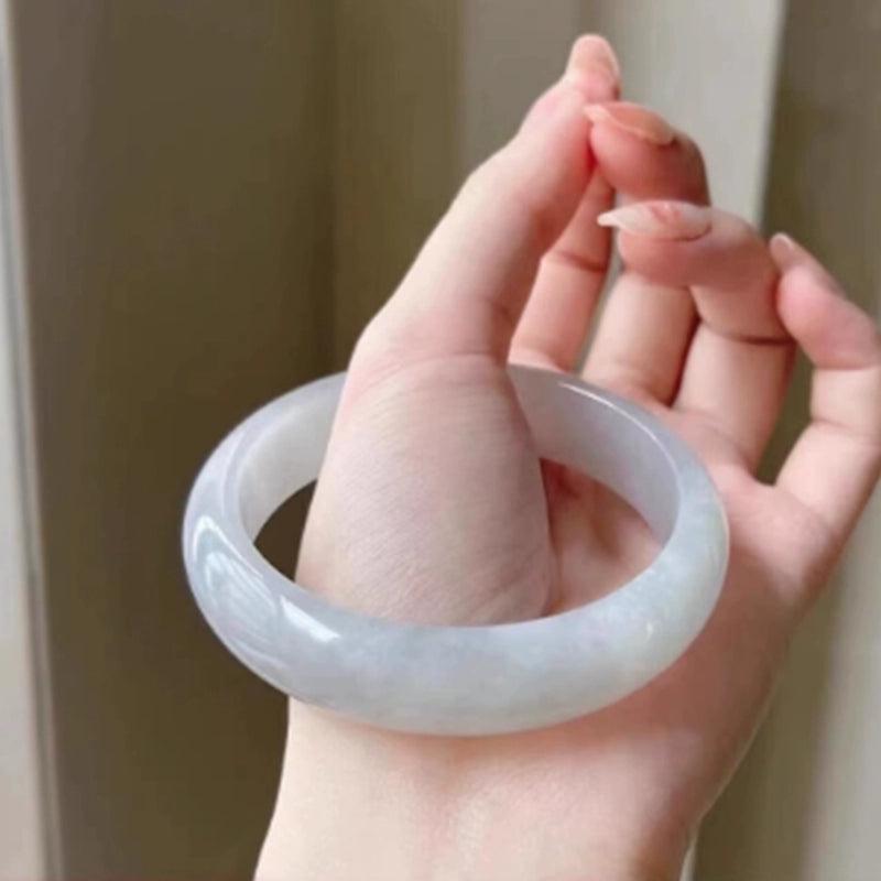 Natural icy white jade bangle held in hand, showing smooth glossy finish and full round shape | DIY Jade
