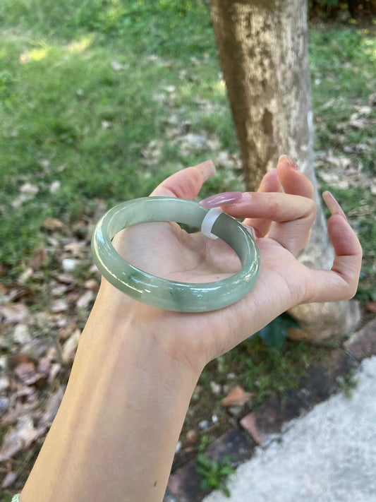 Natural light green icy jadeite bangle held in hand outdoors, showing color under natural sunlight | DIY Jade