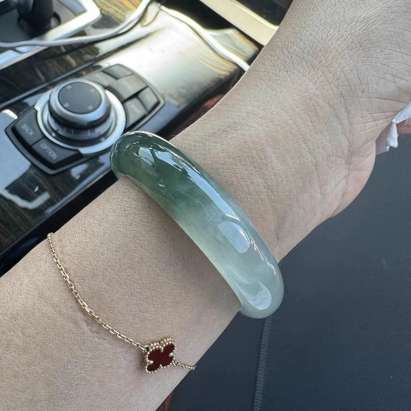 Natural light green jadeite bangle bracelet worn on wrist in car, everyday lifestyle shot | DIY Jade
