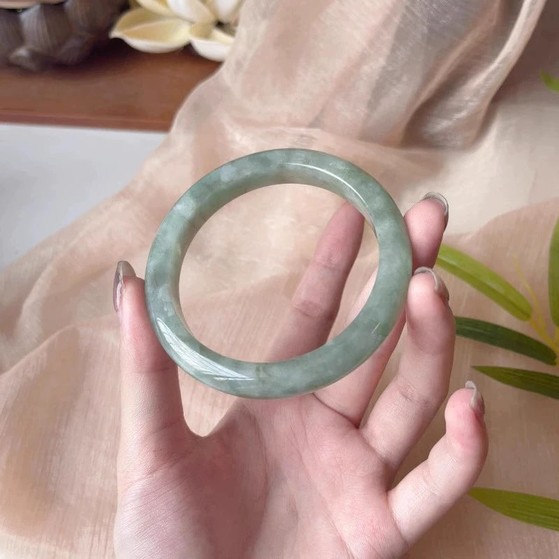 Natural light green mottled jadeite bangle, held in hand to show natural texture and color | DIY Jade
