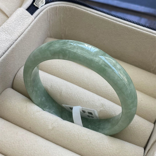 Natural light green mottled jadeite bangle in soft jewelry case, showing glossy finish | DIY Jade