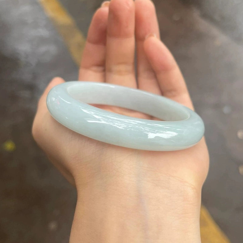 Light white jadeite bangle bracelet held flat in hand, showing elegant profile | DIY Jade