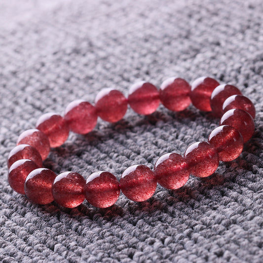 Natural pinkish-red strawberry quartz round bead bracelet with sparkling inclusions, displayed on textured fabric | DIY Jade