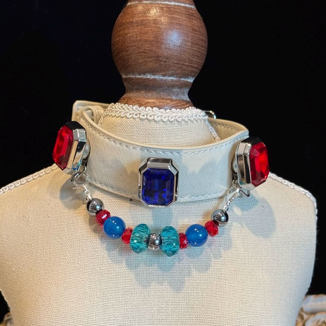 Off‑white pet collar with red‑blue square gems and bright crystal bead chain on display bust | DIY Jade