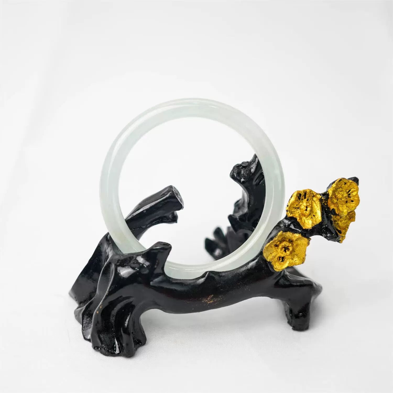 Pale green jade bangle displayed on black floral stand, elegant aesthetic shot | DIY Jade

