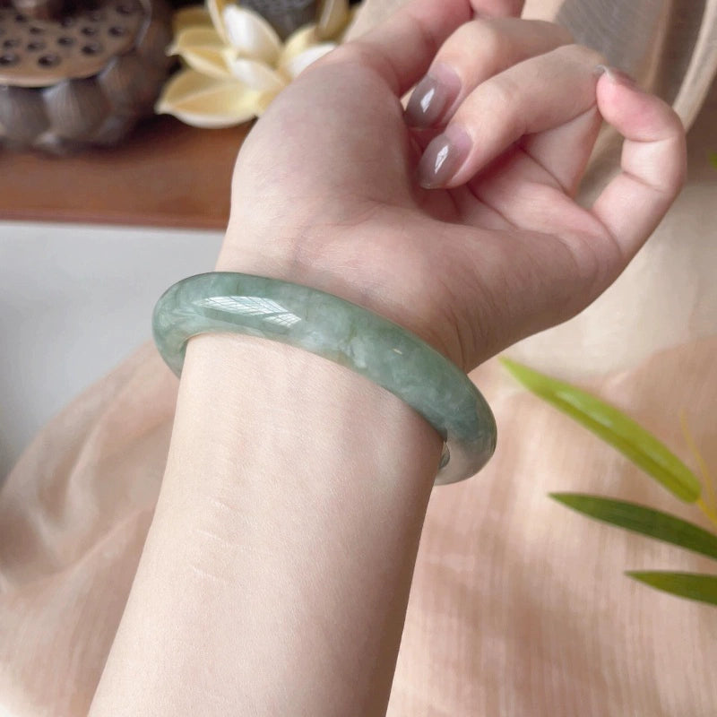 Pale green jadeite bangle bracelet worn on wrist, elegant lifestyle shot with natural decor | DIY Jade