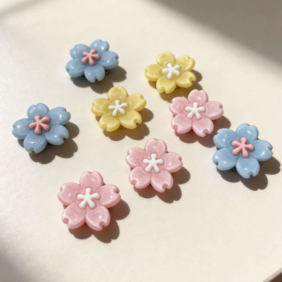 Pastel sakura flower pet collar charms pink blue yellow flat lay product shot | DIY Jade
