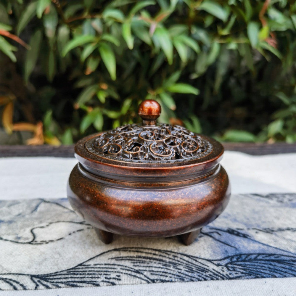 Reddish-brown incense burner with carved lid, outdoor closeup with plants | DIY Jade