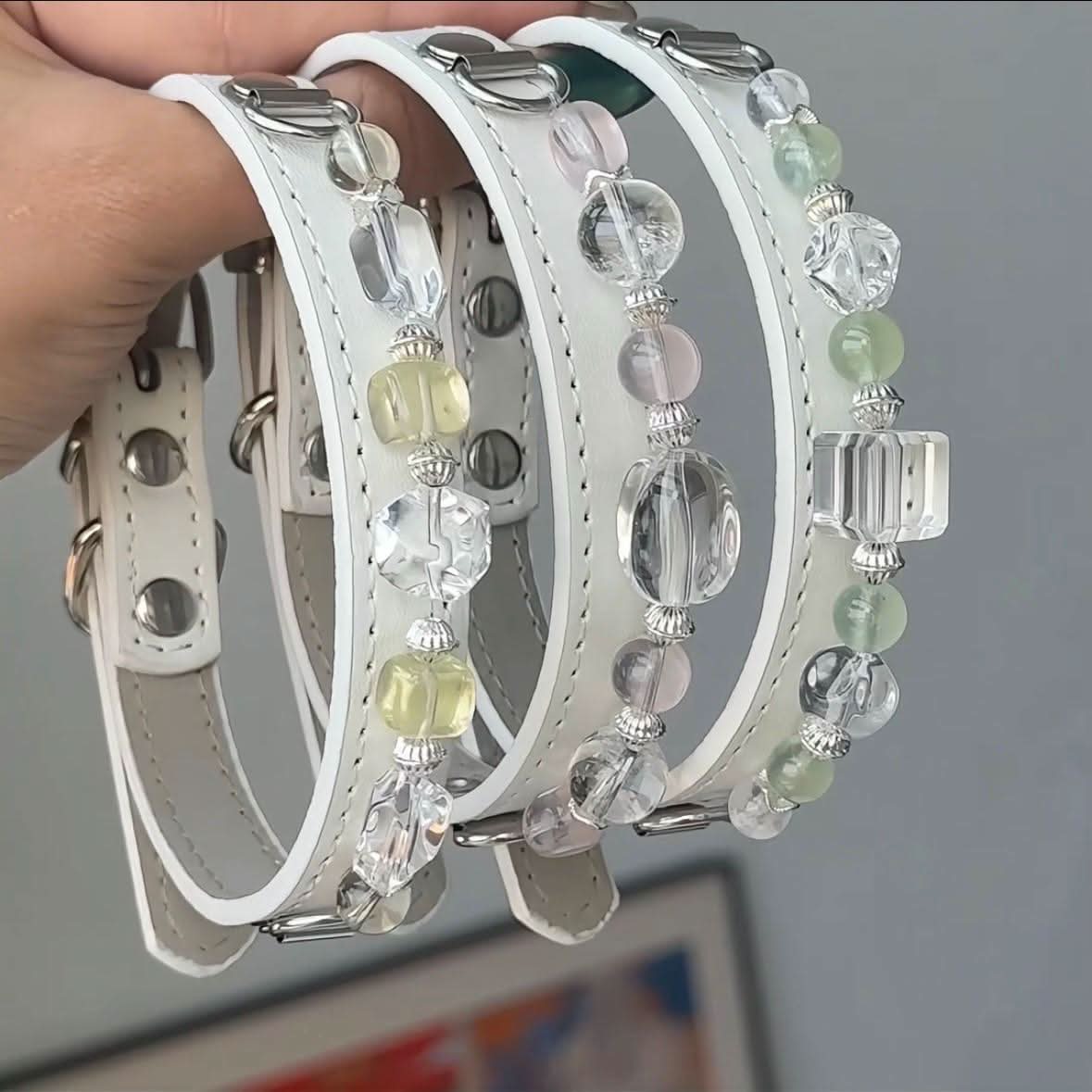 Hand holding multiple white leather pet collars with clear and light green gem beads | DIY Jade
